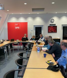 Personen sitzen an einem Tisch in U-Form