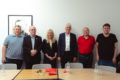 Katrin ist umringt von Männern vor einer Wand